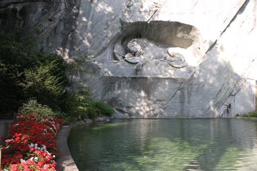 Photograph of Lion Monument with a small pond and flower in the foreground - Switzerland - Europe